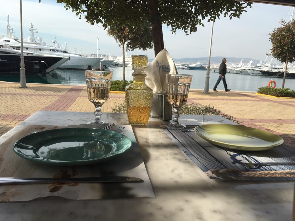 Outdoor restaurant table in front of docked yachts