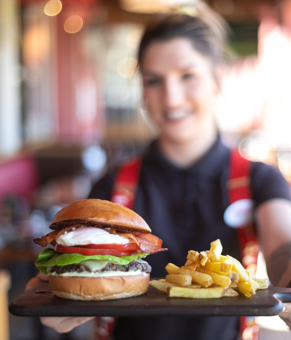 Γυναίκα που κρατάει δίσκο με burger και πατάτες