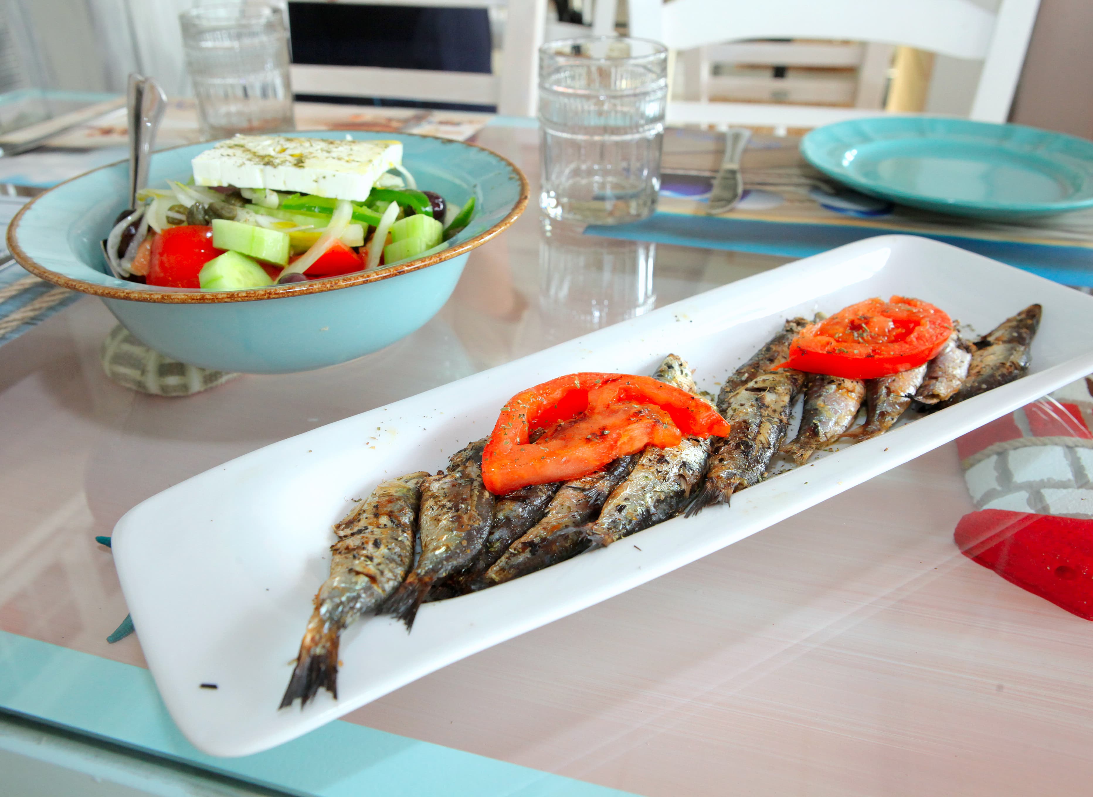 Grilled fish dish and Greek salad on table