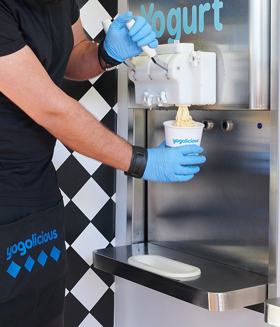 Ανδρας που σερβίρει frozen yogurt σε κυπελλάκι από το μηχάνημα