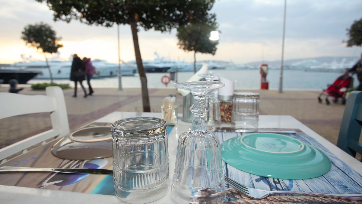 Outdoor table in front of docked yachts at Nisos Restaurant in Flisvos Marina, Athens