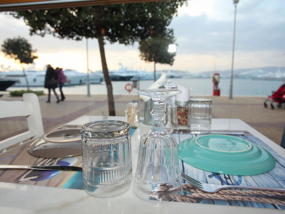 Outdoor table in front of docked yachts at Nisos Restaurant in Flisvos Marina, Athens