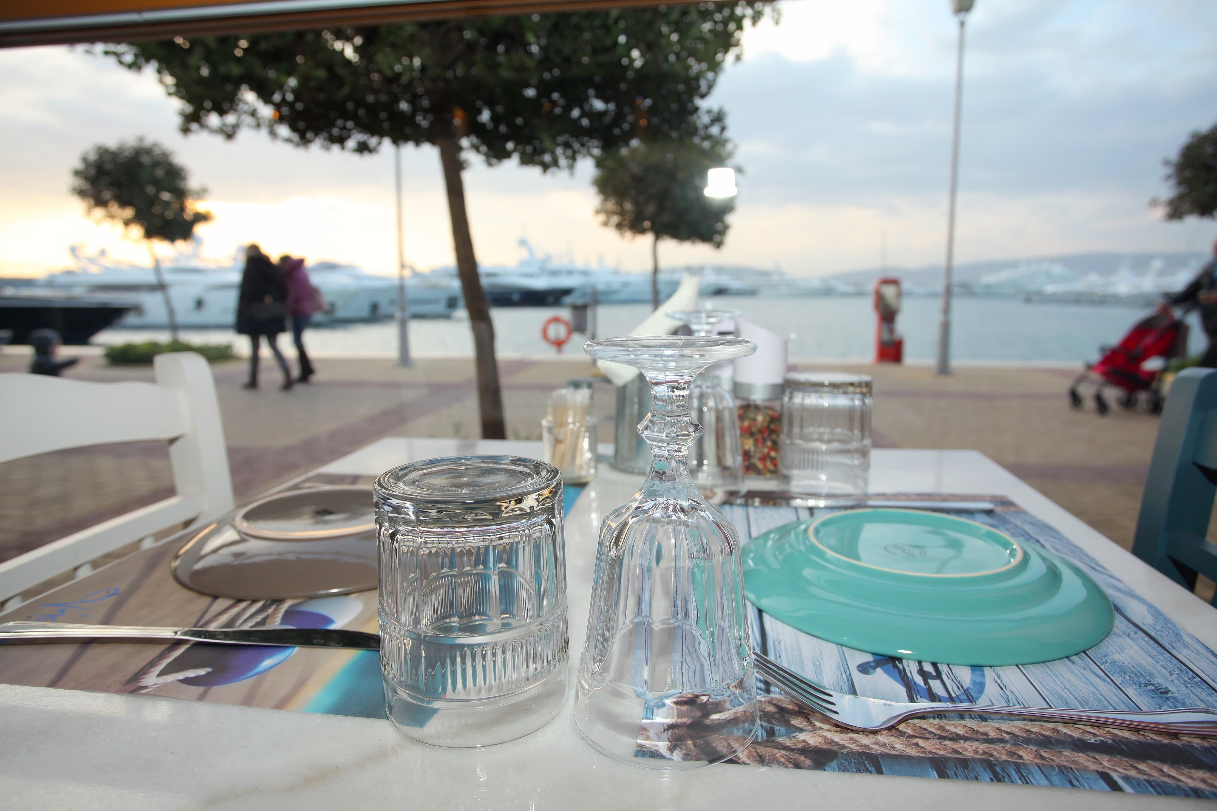 Outdoor table in front of docked yachts at Nisos Restaurant in Flisvos Marina, Athens